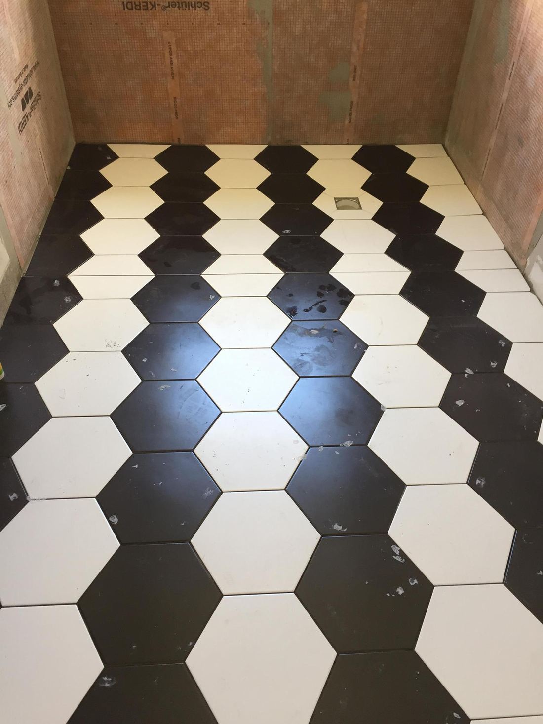 Sol en carreaux hexagonaux noirs et blancs en cours de pose